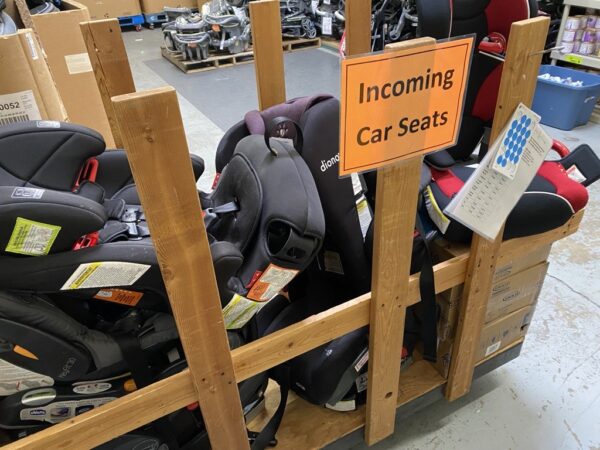 Bin filled with donated car seats labeled “Incoming” at WestSide Baby’s Seattle warehouse.