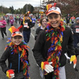 Families running in a Seattle-area Turkey Trot wearing festive Thanksgiving costumes and enjoying a community 5K event.