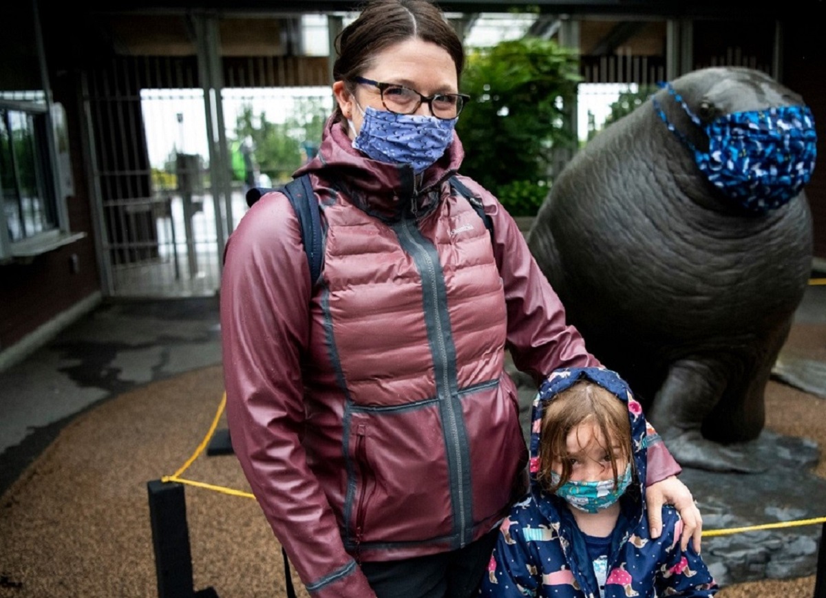 Woman and child wearing masks in front of zoo