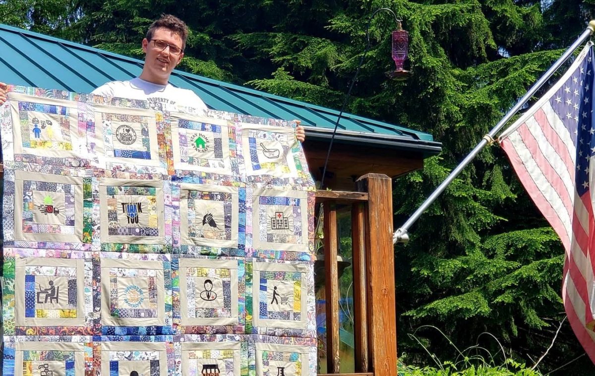 boy displaying handmade quilt