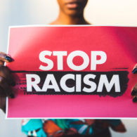 hands holding sign saying "no racism"