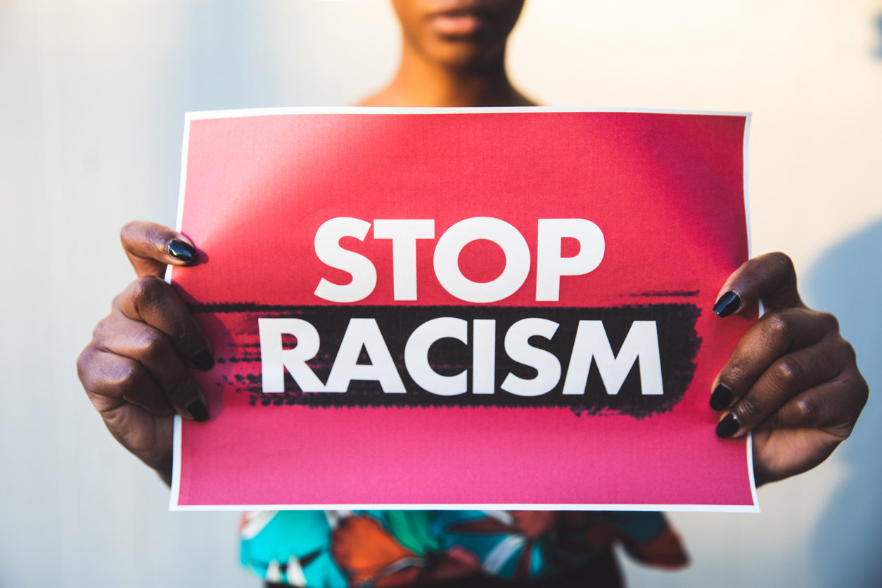 hands holding sign saying "no racism"