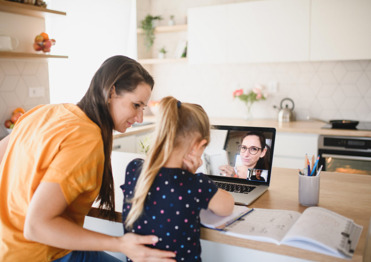 COVID-19 parents: Mother patting daughter on the back, while daughter is on a Zoom call