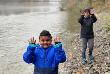 Hikes: two boys in raincoats holding their hands up next to the Snoqualmie river