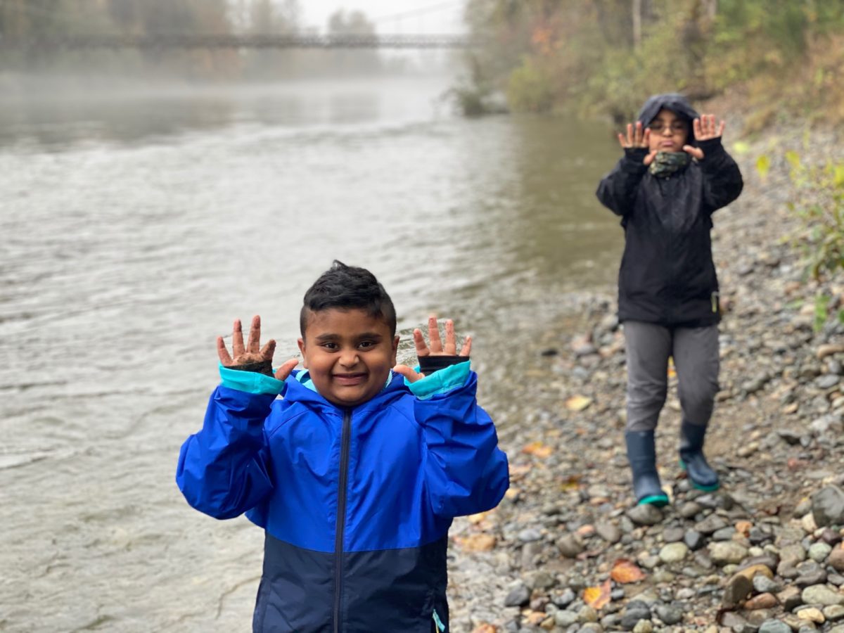 Hikes: two boys in raincoats holding their hands up next to the Snoqualmie river