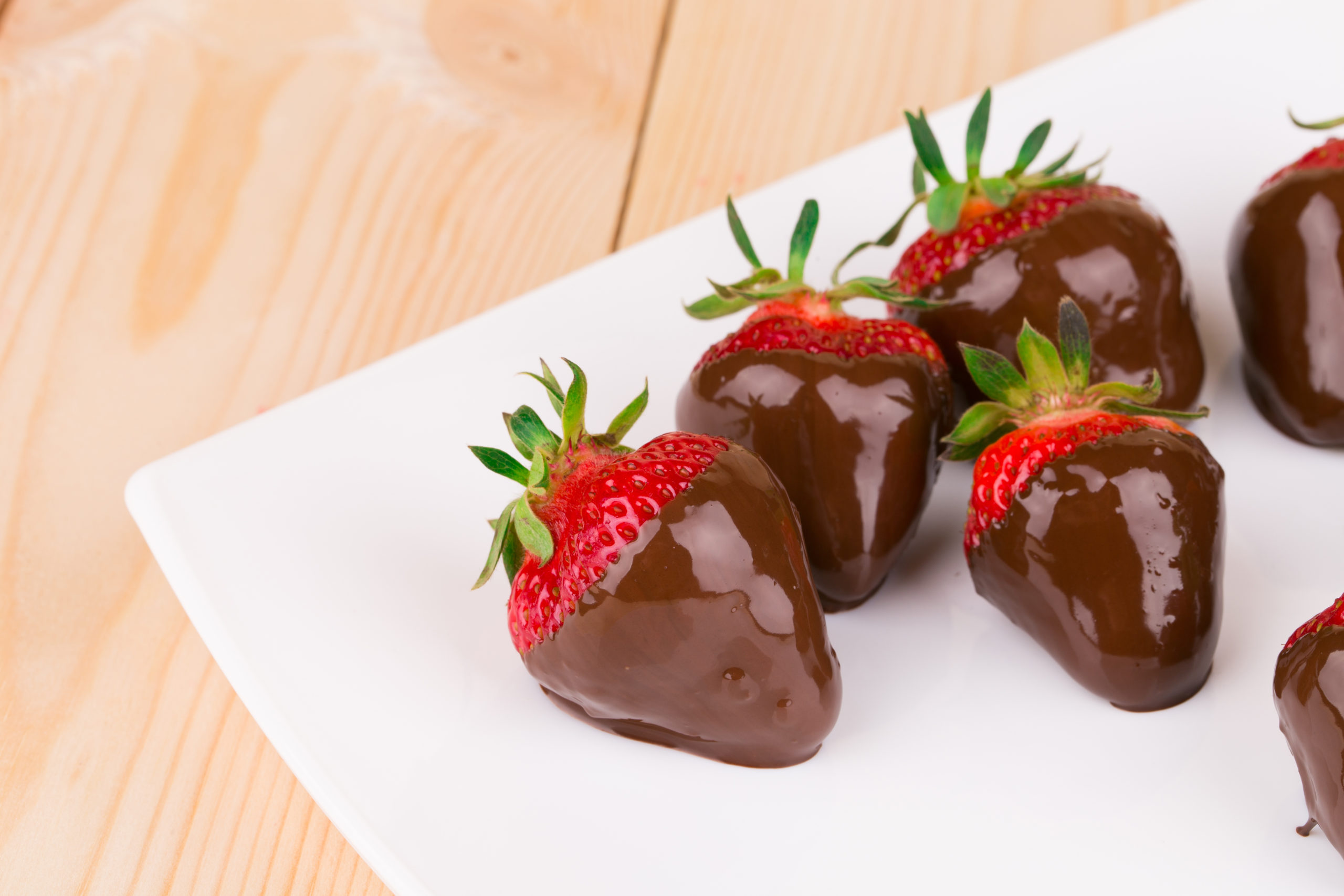 Four chocolate dipped strawberries on a plate