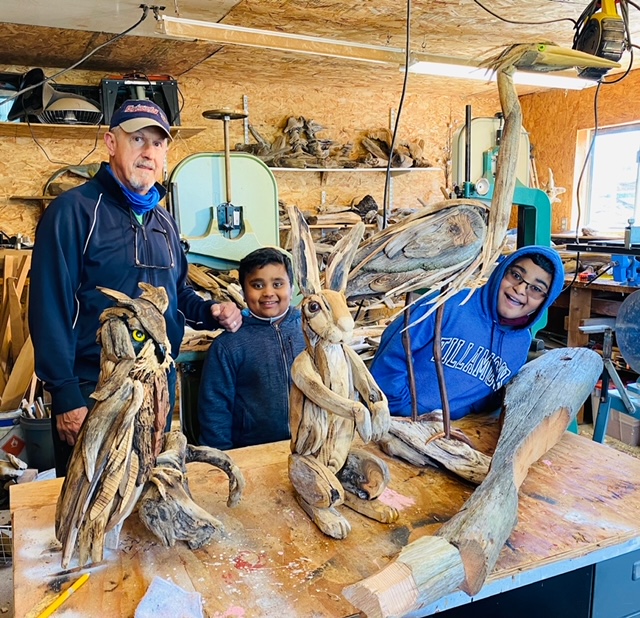 Artist Joe Treat stands with visitors in his workshop
