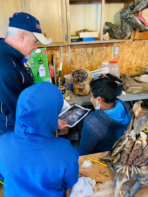 The artists shows the kids Sasquatch pictures, aiding him in his next project.