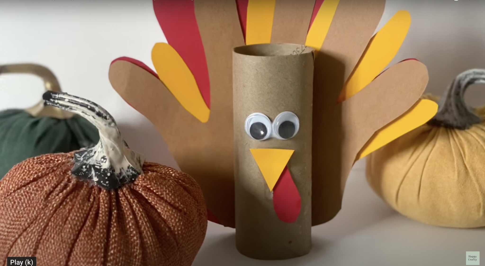 3-D Thanksgiving turkey craft made from a toilet paper roll with paper handprint feathers, googly eyes, and a small paper beak.