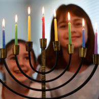 Smiling kids gather in front of a glowing menorah during a Chanukah celebration in Seattle.