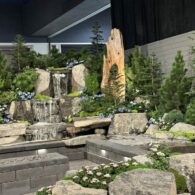 Stone slabs create a set with a waterfall, trees, and flowers at the Flower and Garden Festival in Seattle.