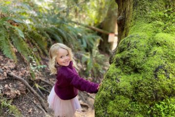Little girl in the middle of a hiking trail, smiling at camera.