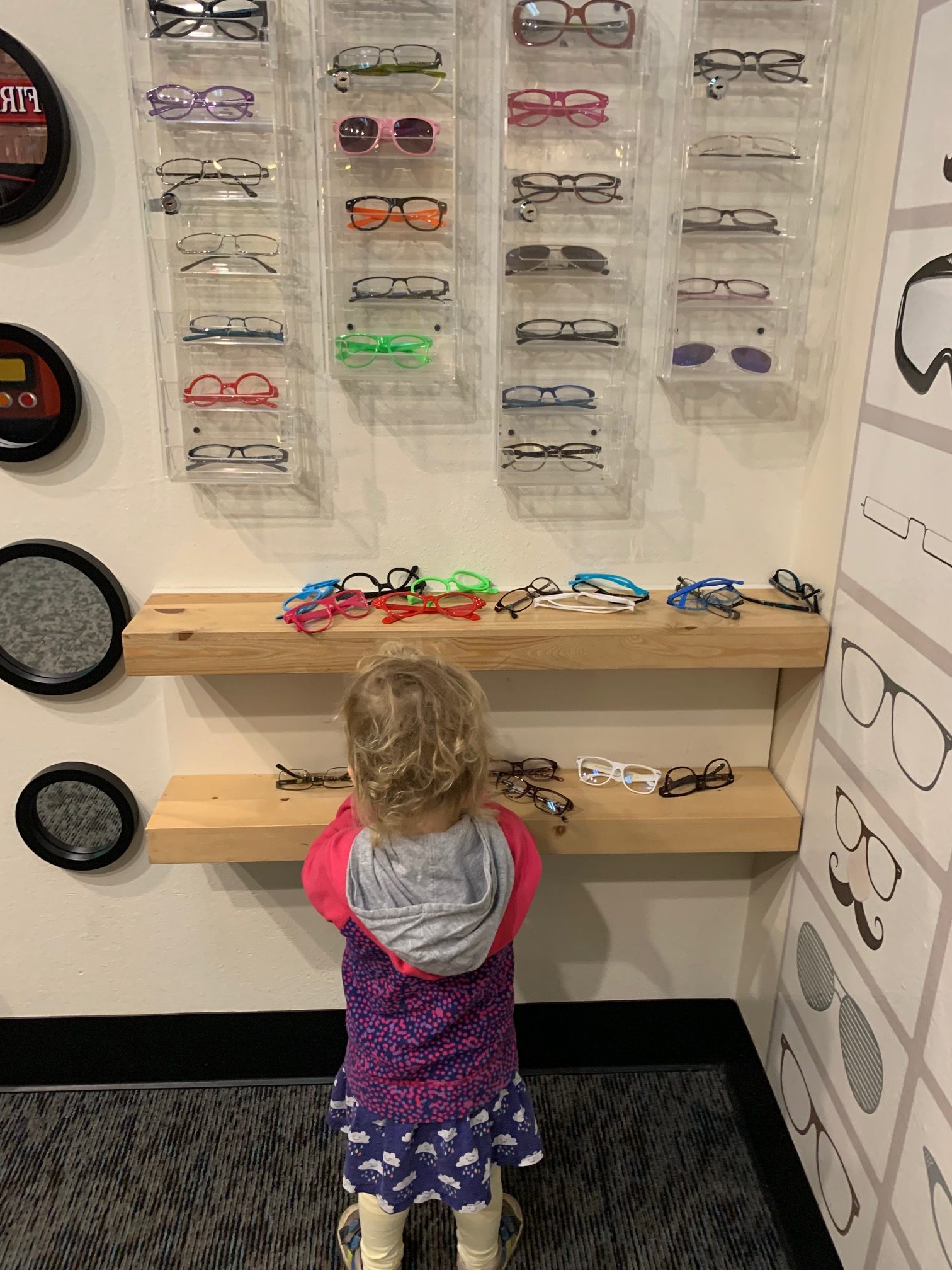 A young girl tries on eyeglass frames.