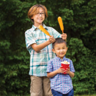 Two kids smiling and holding fair food at a summer fair