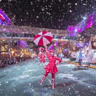 Snowflake Lane performer dancing along Bellevue Way in Bellevue, surrounded by lights, holiday decorations, and falling snow.