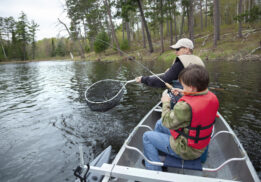 A boy wearing a life jacket fishing with his dad Free Fishing Weekend