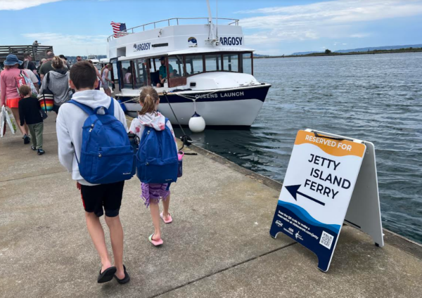 Children walking toward the Jetty Island ferry sign at the Everett marina on a sunny day