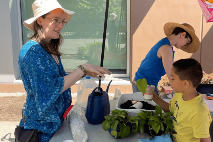 A volunteer helping a child learn about plants at the Beacon Arts Street Fair is July 8th, 2023