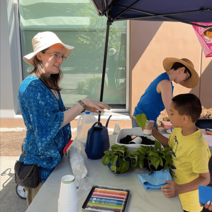 A volunteer helping a child learn about plants at the Beacon Arts Street Fair is July 8th, 2023