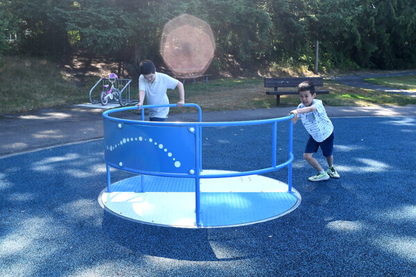 Kids pushing the blue merry-go-round.
