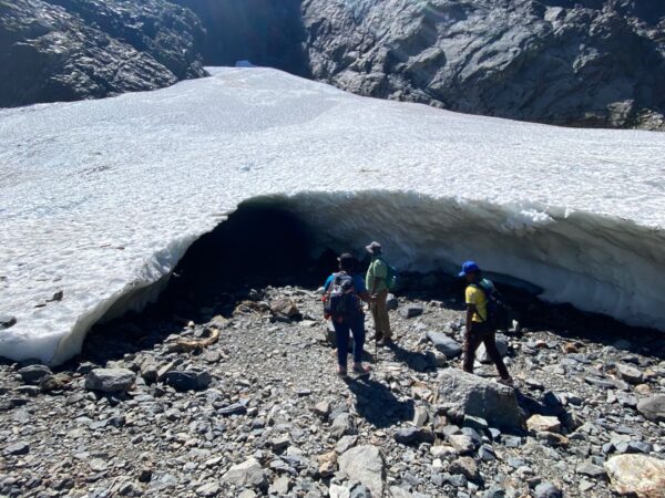 Family walking toward the Big Four Ice Caves, with visible warning signs nearby advising visitors to keep out for safety.