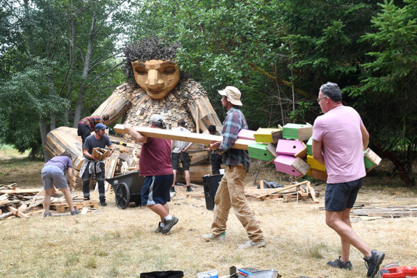 A bird house is being walked away to another location by artists