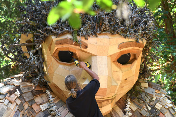 A volunteer is fixing the eye of the giant troll
