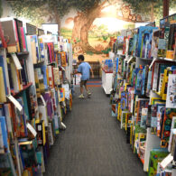 Child browsing books in the kids’ section of a bookstore, surrounded by colorful shelves and displays
