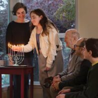 A Seattle family lighting the Chanukah menorah together, with children watching the candles glow during the Festival of Lights.
