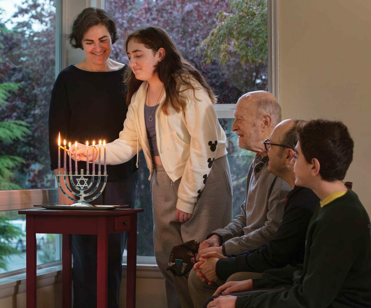 A Seattle family lighting the Chanukah menorah together, with children watching the candles glow during the Festival of Lights.