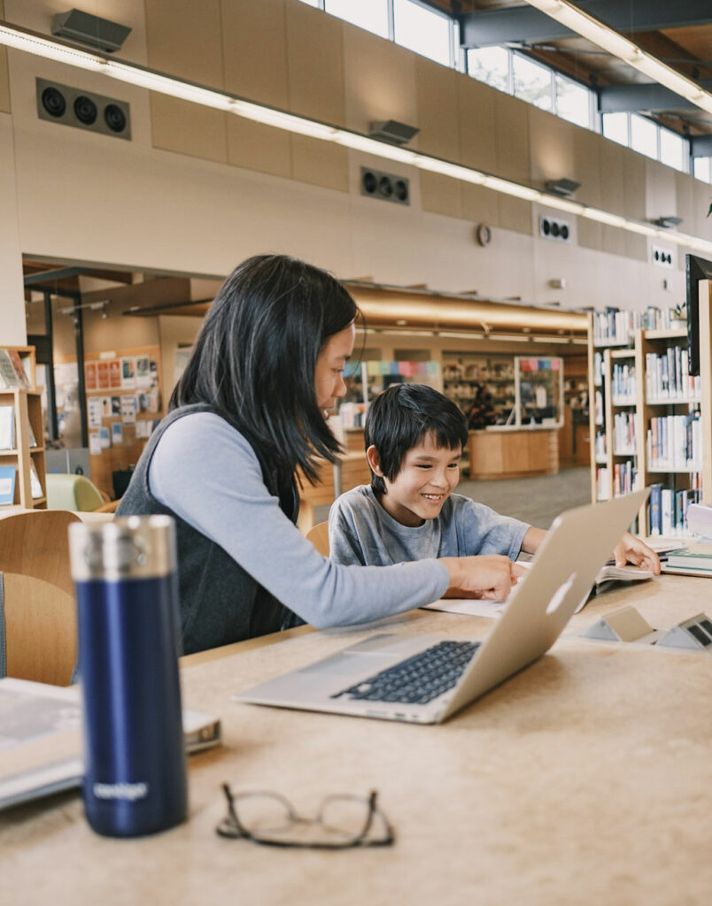 Mother and son looking at a laptop computer on a table at the Seattle Public Library
