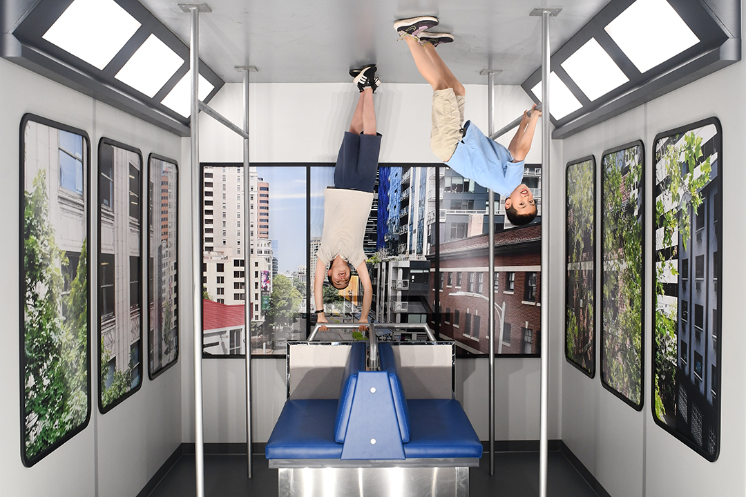 Two kids appearing to hang upside down on the Monorail illusion.