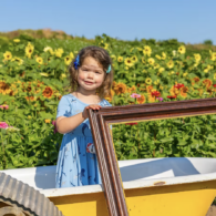 Two children posing with sunflowers and festival food at a Washington farm