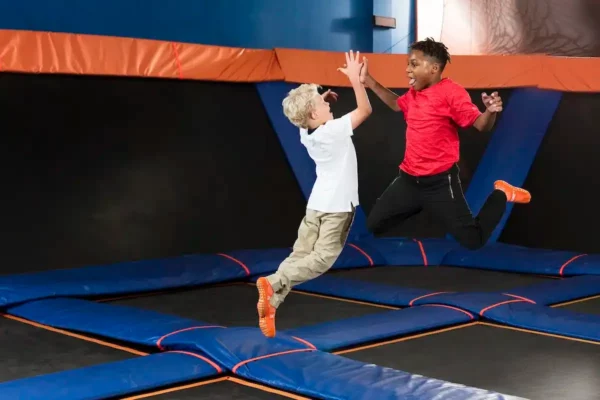 Two kids jumping and high-fiving at Sky Zone indoor trampoline park