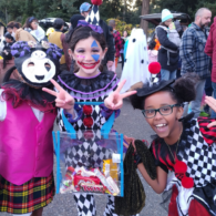 Kids in Halloween costumes posing beside decorated cars at a Trunk-or-Treat event near Seattle.