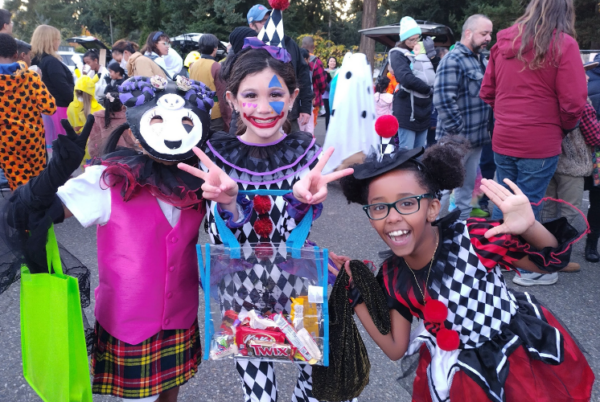 Kids in Halloween costumes posing beside decorated cars at a Trunk-or-Treat event near Seattle.