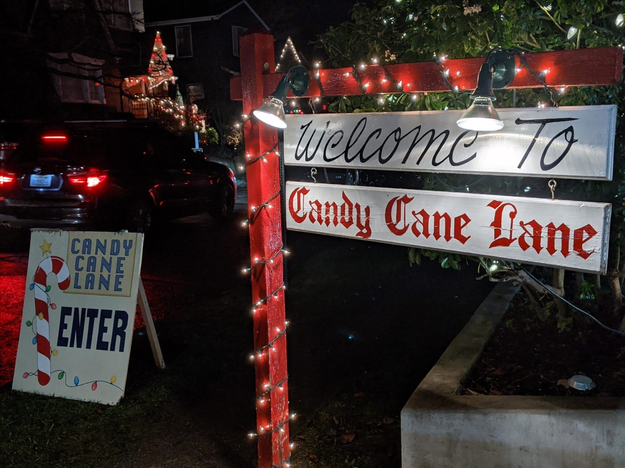 A festive wooden sign marking the entrance to Seattle’s Candy Cane Lane in the Ravenna neighborhood, decorated with lights for the holiday season.