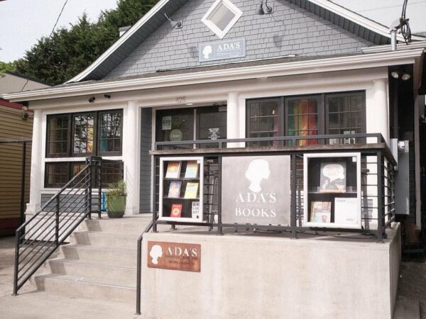 Exterior shot of Ada's Technical Books, showing a traditional gray home turned bookstore with signs in the windows.