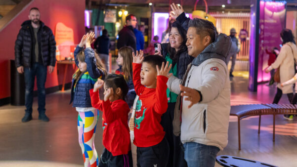 A family smiling and holding their hands up in the air.