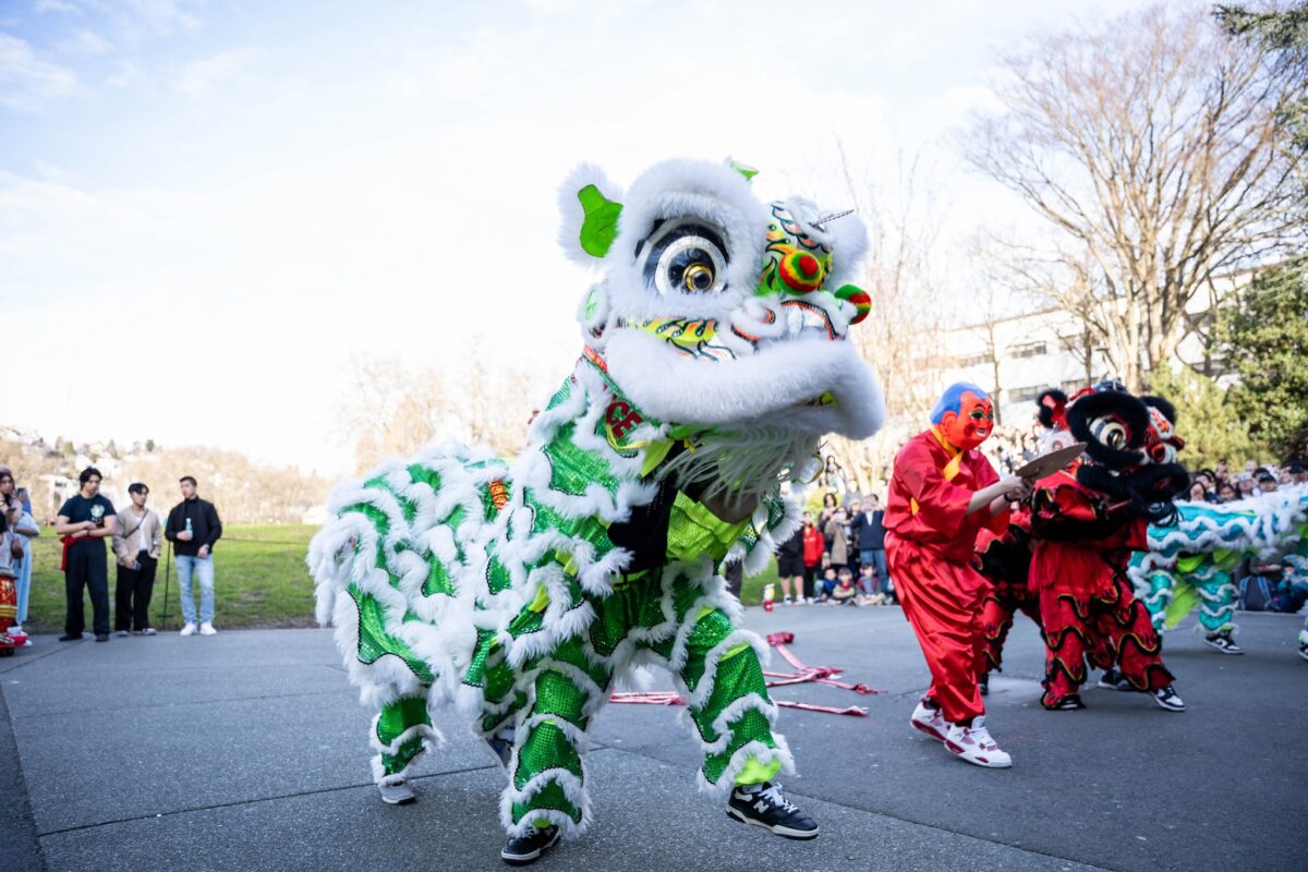 Green and white lion participate in traditional Lion Dance in street, onlookers line street watching.