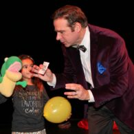 Magician and child hold puppet for trick.