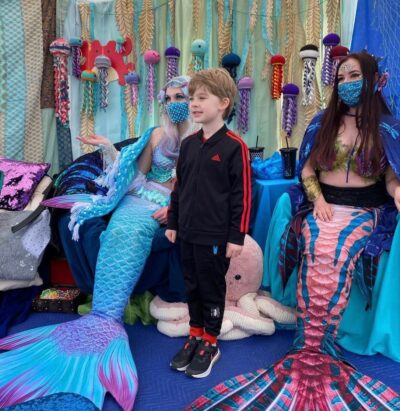 Kid standing with mermaids