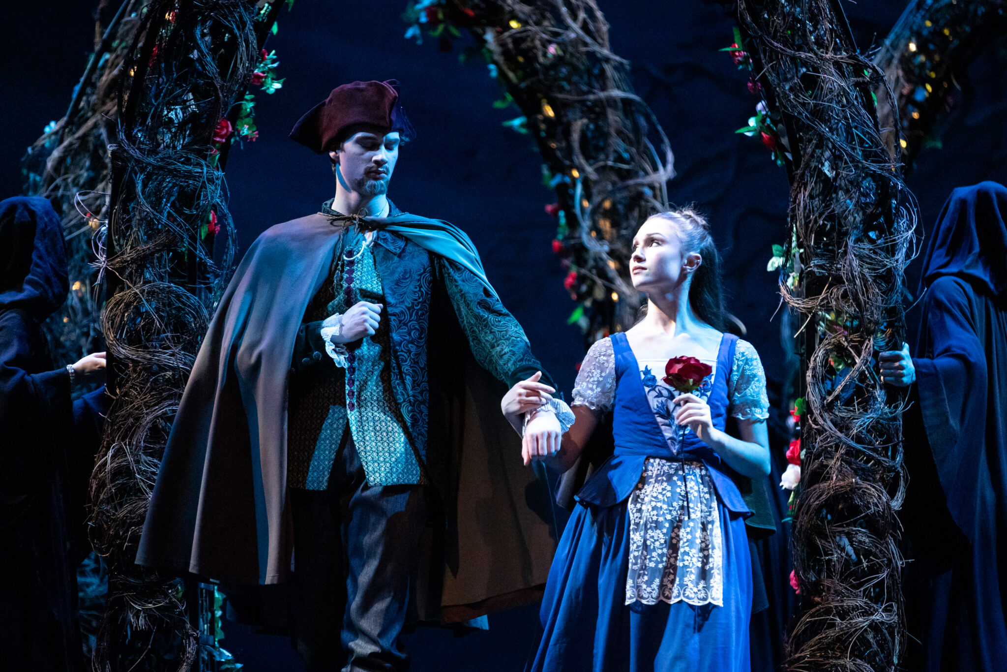 Female and male dancers hold hands on stage, female dancer holds a rose