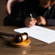 Judge writing on paper on desk, gavel next to it