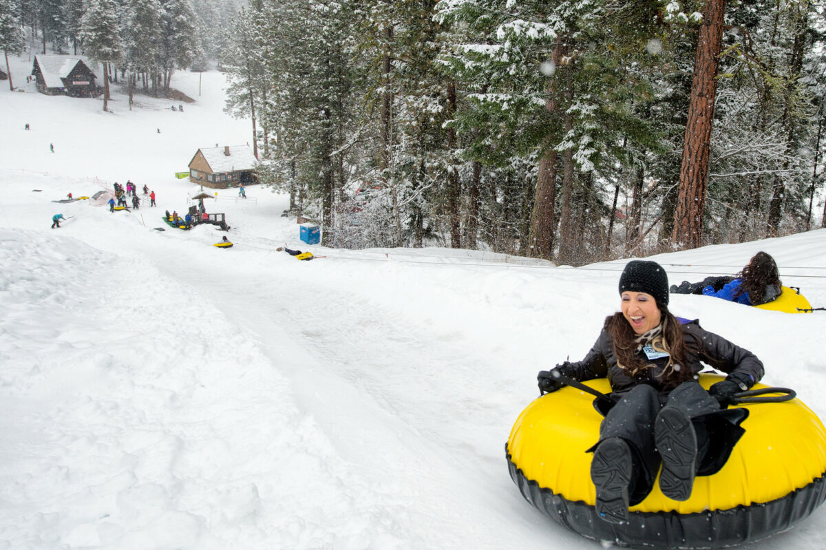 Woman in a tub at the top of the tubing hill smiles as she's about to go down