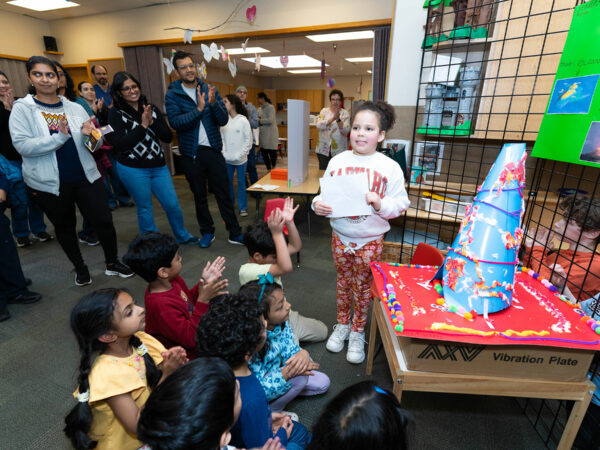 Student standing in front of an audience of other elementary students and their parents to present her science fair project at Sammamish Montessori