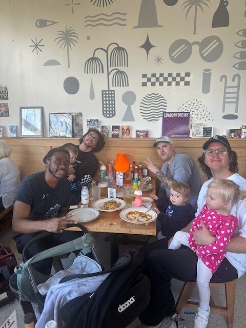 Bunch of dads and kids crowd around a table and smile at the camera