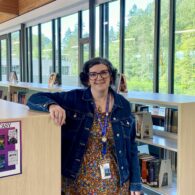 Woman poses next to bookshelf