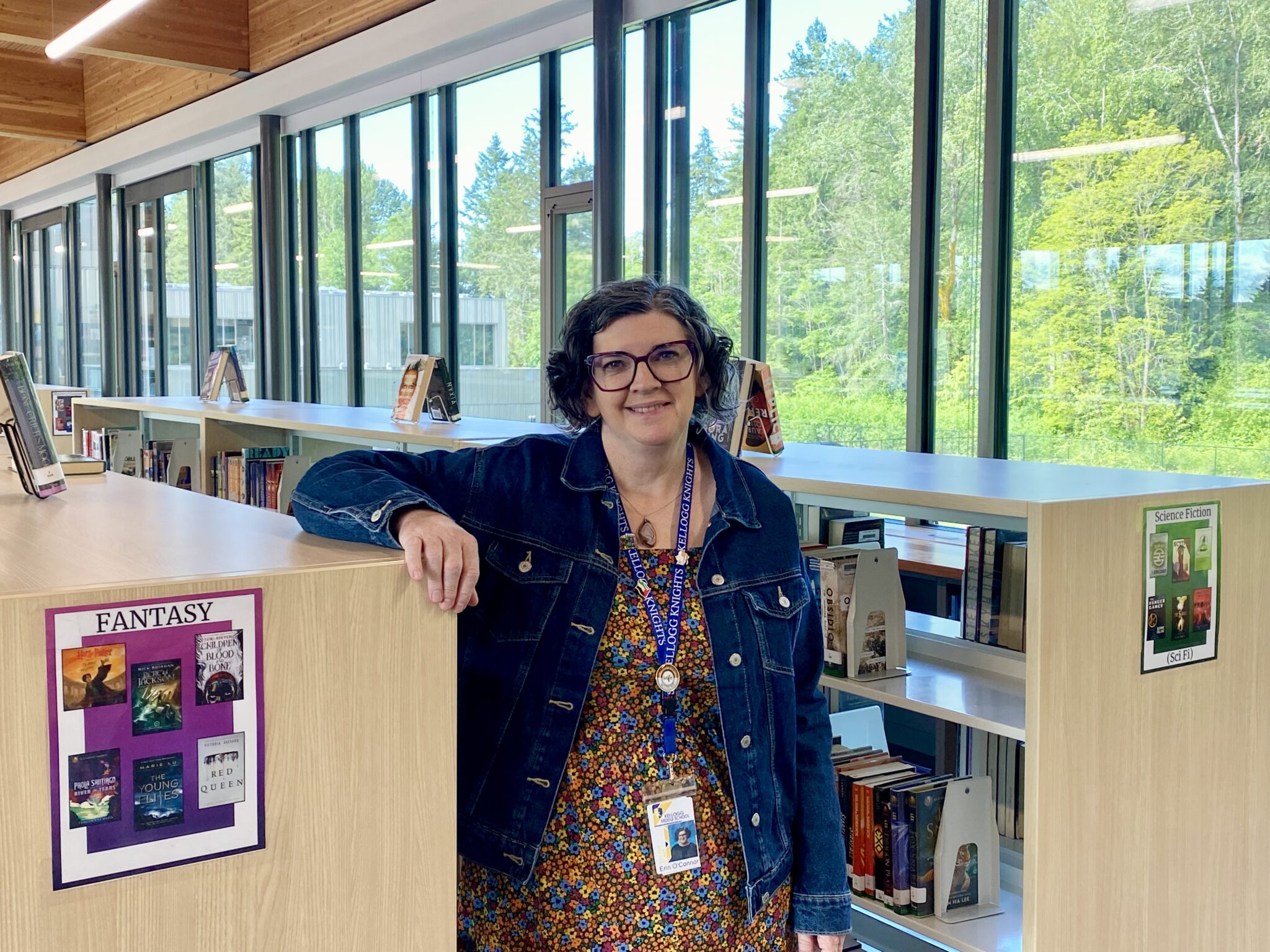 Woman poses next to bookshelf