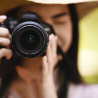 Female Photographer Taking Shot Outdoors With Modern Camera, Selective Focus On Lens